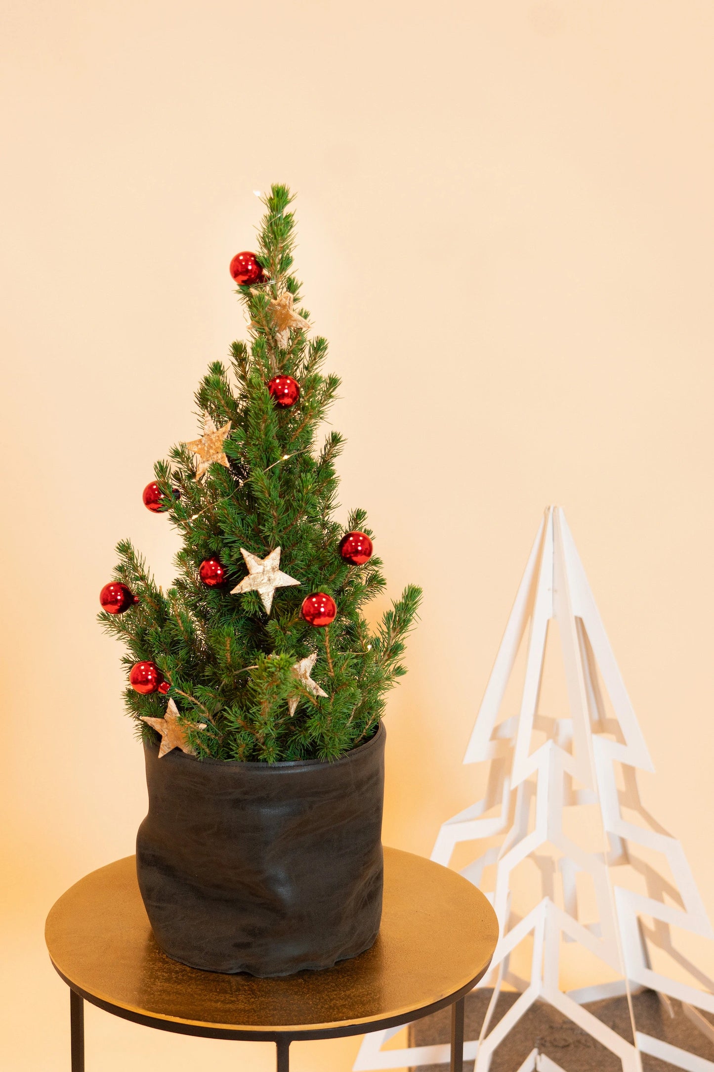 Echt versierd kerstboompje Sfeervol verpakt kerstboompje met glinsterende ornamenten en feestelijke linten, klaar om de magie van Kerstmis in huis te brengen